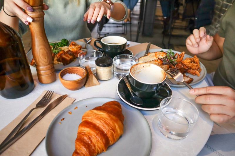 Vibrant breakfast spread with croissant, coffee, and various dishes on a table - representing the breakfast culture discussed in this article